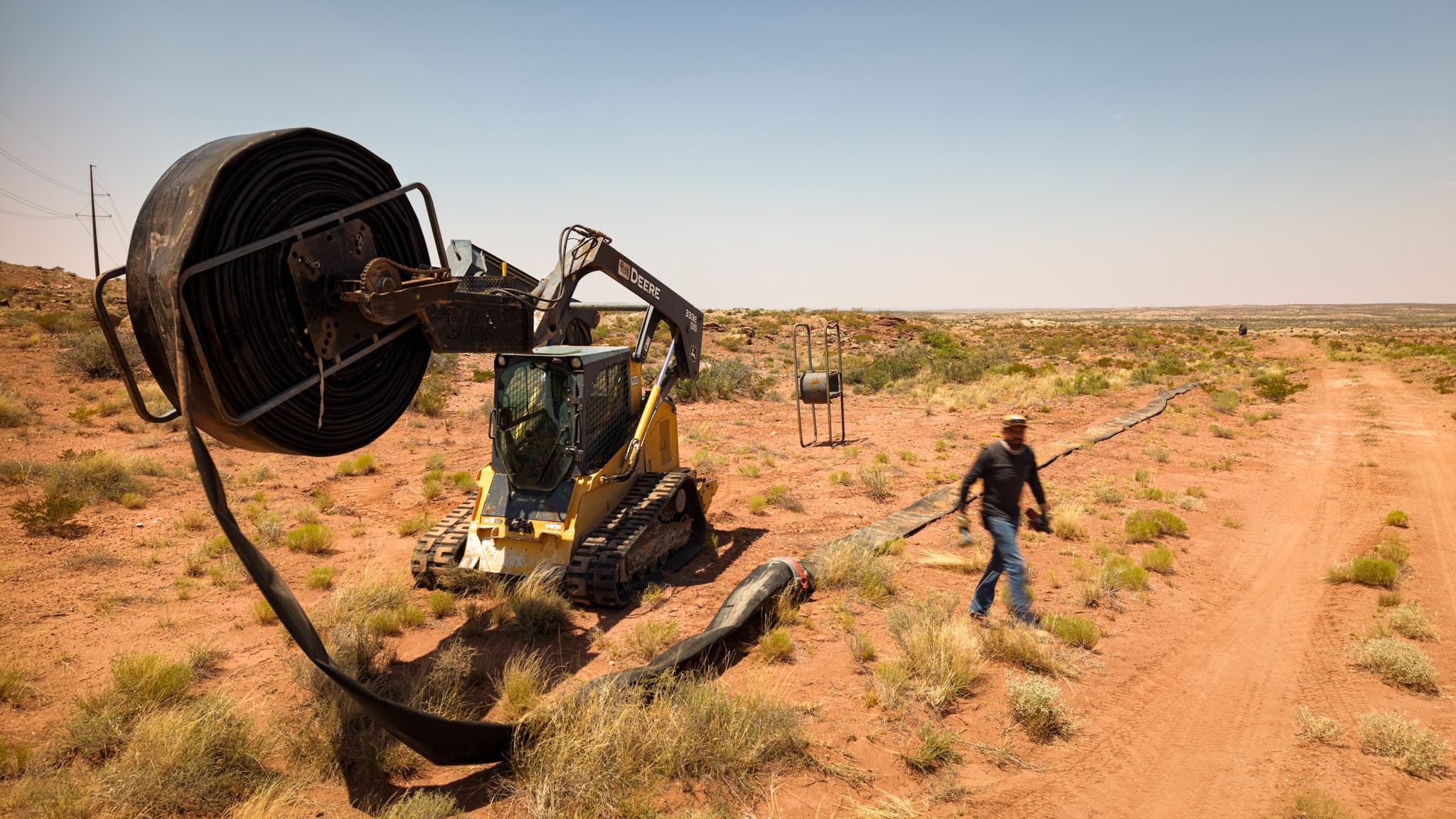 Alfadale crew deploying layflat piping for oilfield water transfer in North Eddy County, New Mexico